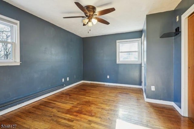 empty room featuring baseboards, wood finished floors, and a ceiling fan