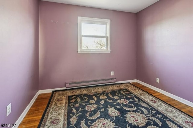spare room with baseboards, wood finished floors, and baseboard heating
