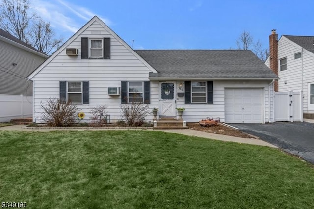 view of front of property featuring fence, an attached garage, a front lawn, aphalt driveway, and a wall unit AC