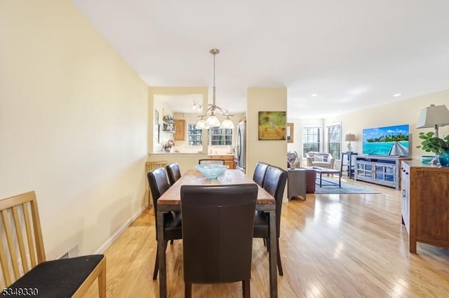 dining room with light wood-type flooring and a chandelier
