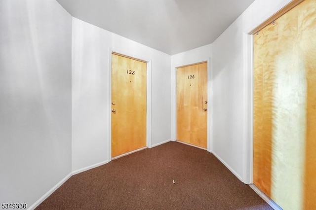 spare room featuring baseboards and dark colored carpet