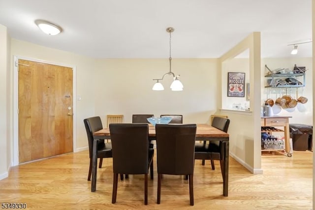 dining space featuring baseboards, a notable chandelier, and light wood-style flooring