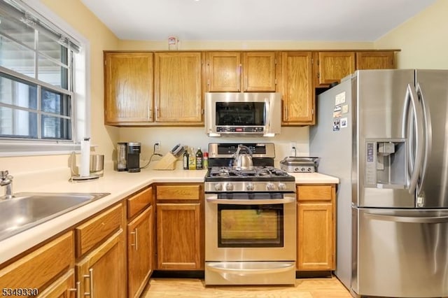 kitchen with light countertops, a sink, brown cabinets, and stainless steel appliances