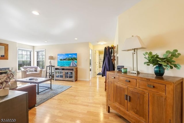 living room featuring recessed lighting, baseboards, and light wood finished floors