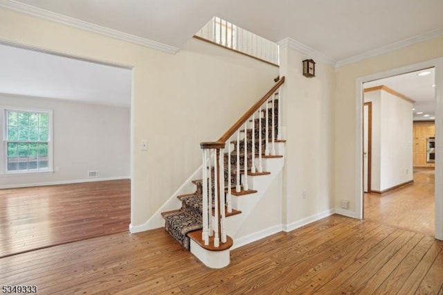 stairway featuring wood-type flooring, crown molding, and baseboards