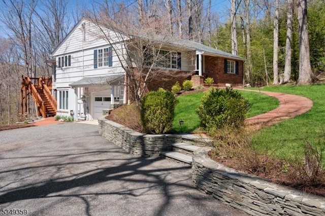 view of front of property with an attached garage, driveway, stairway, and brick siding