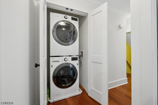 laundry area with laundry area, stacked washer and clothes dryer, dark wood-style flooring, and crown molding