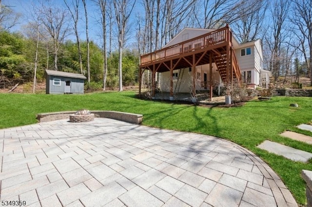 view of patio featuring a deck, an outbuilding, a storage unit, a fire pit, and stairs