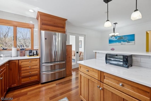 kitchen featuring freestanding refrigerator, a toaster, light countertops, light wood finished floors, and decorative light fixtures