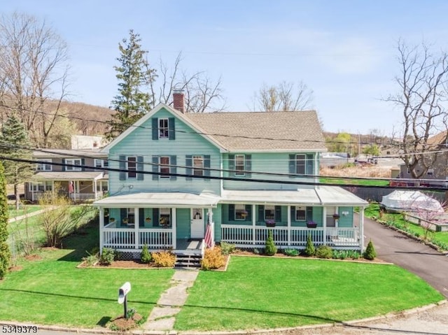 view of front of house featuring a porch, a chimney, fence, and a front lawn