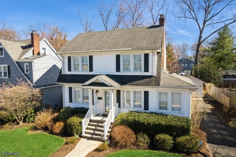 view of front of property with a chimney, a shingled roof, and fence
