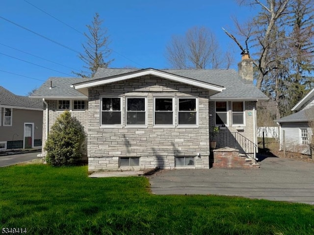 back of property with a lawn, a chimney, and a shingled roof