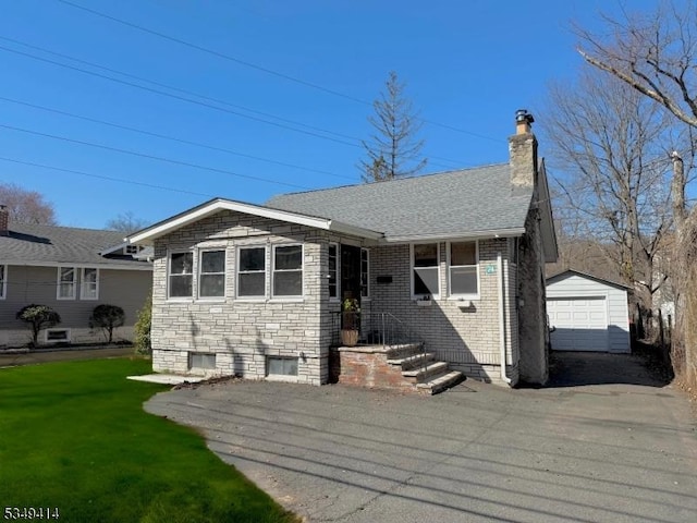 view of front of property with aphalt driveway, a chimney, a detached garage, an outdoor structure, and a front lawn