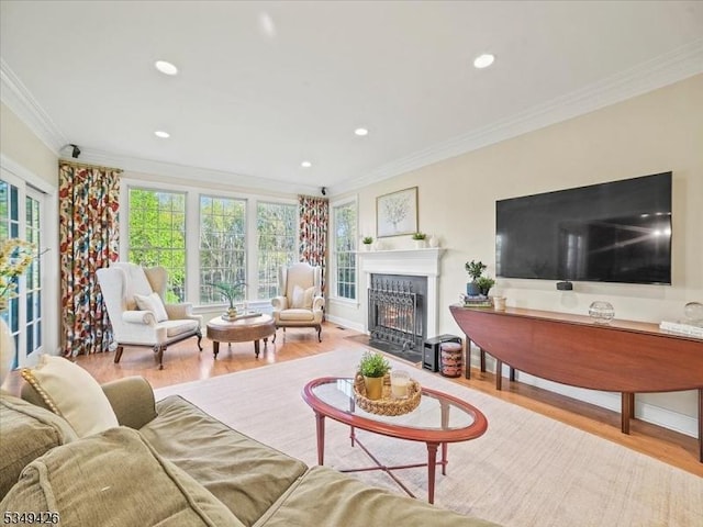 living area with crown molding, recessed lighting, a fireplace with flush hearth, and wood finished floors