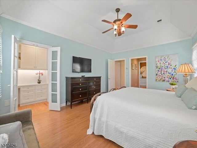 bedroom featuring ensuite bathroom, visible vents, a raised ceiling, light wood-style floors, and ornamental molding