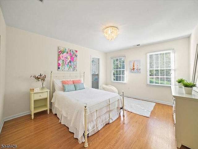 bedroom with baseboards, light wood finished floors, a chandelier, and visible vents