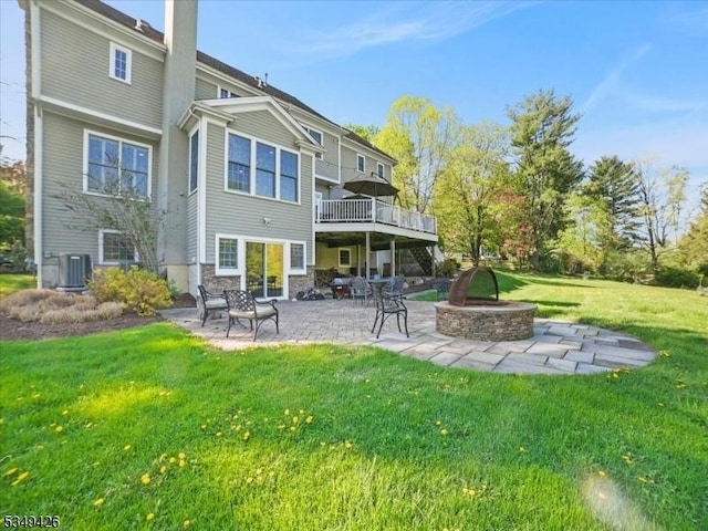rear view of property with cooling unit, a patio, a chimney, an outdoor fire pit, and a yard