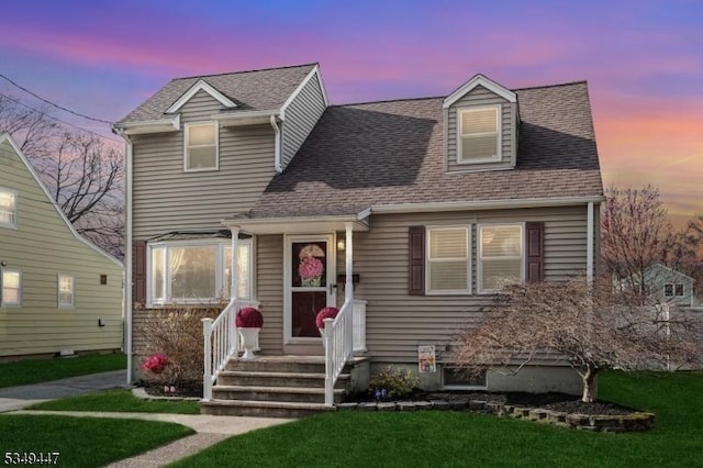 view of front of home featuring a front yard and a shingled roof