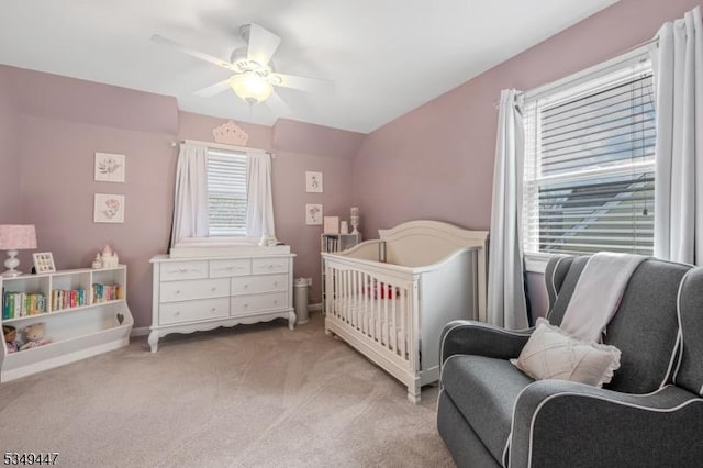 bedroom with baseboards, vaulted ceiling, light colored carpet, and a ceiling fan