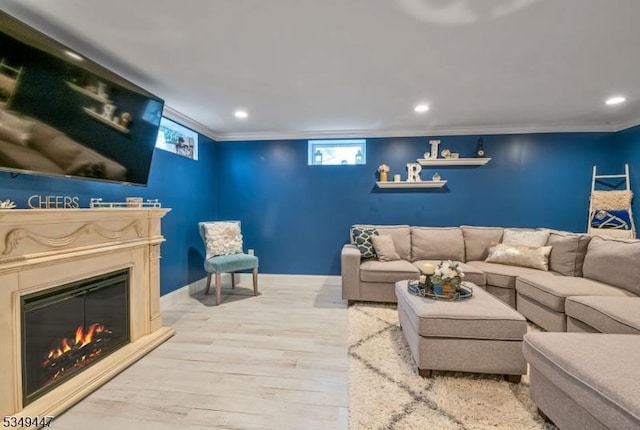 living room with crown molding, recessed lighting, a glass covered fireplace, and wood finished floors