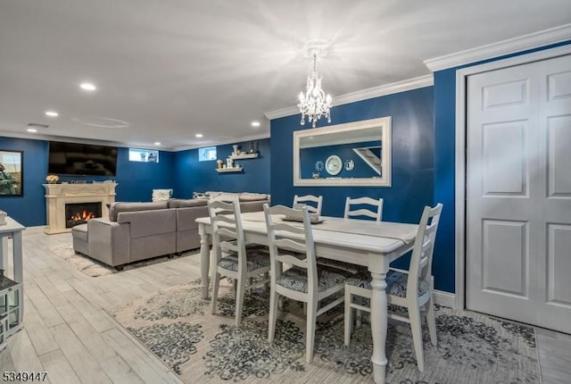 dining room with baseboards, light wood-type flooring, crown molding, recessed lighting, and a lit fireplace