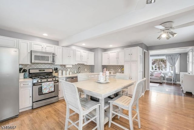 kitchen with white cabinets, light wood-style floors, light countertops, and appliances with stainless steel finishes