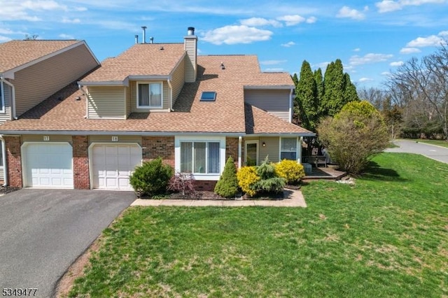 traditional-style home with a front lawn, brick siding, a chimney, a shingled roof, and driveway