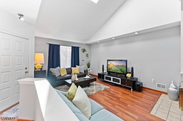 living room featuring visible vents, baseboards, high vaulted ceiling, and wood finished floors