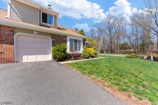 view of home's exterior with brick siding, driveway, an attached garage, and a lawn