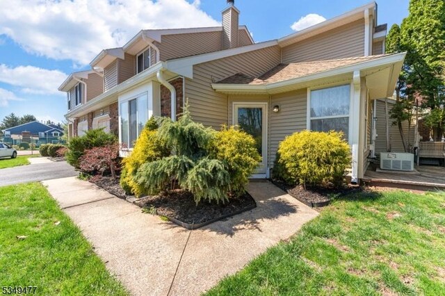 view of property exterior featuring a yard, central air condition unit, and a chimney
