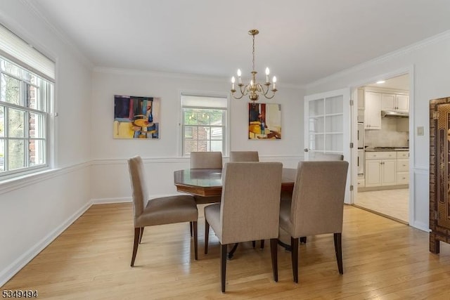 dining space featuring an inviting chandelier, light wood-style floors, ornamental molding, and baseboards