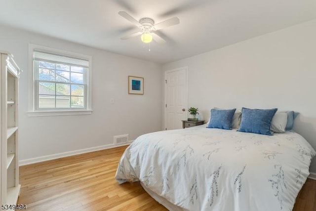 bedroom with a ceiling fan, visible vents, light wood-style flooring, and baseboards