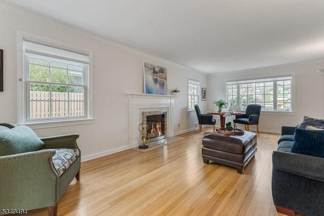 living area with baseboards, a tile fireplace, light wood-style floors, and crown molding