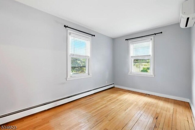 59 James St, Morristown Town, NJ 07960 - spare room with a baseboard radiator, a wall unit AC, and wood-type flooring