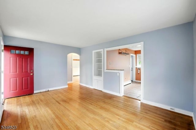 59 James St, Morristown Town, NJ 07960 - unfurnished living room featuring arched walkways, built in features, light wood-style floors, and a baseboard heating unit