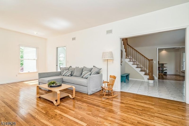 living room featuring stairway, baseboards, and wood finished floors