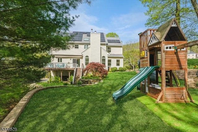 view of play area featuring a yard, stairs, and a wooden deck