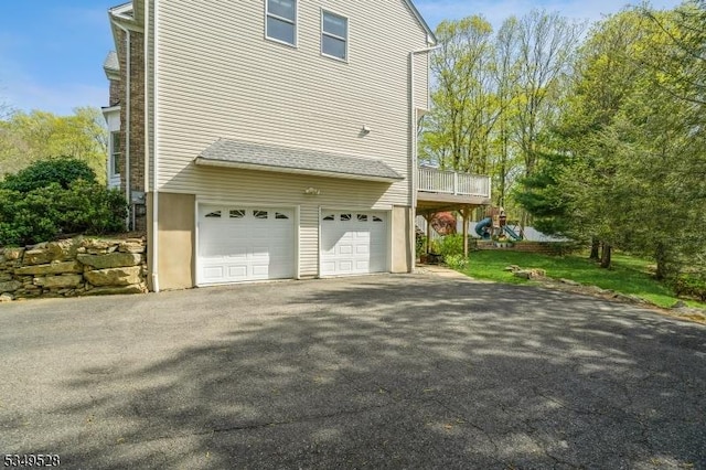 view of side of home with driveway, an attached garage, and a deck