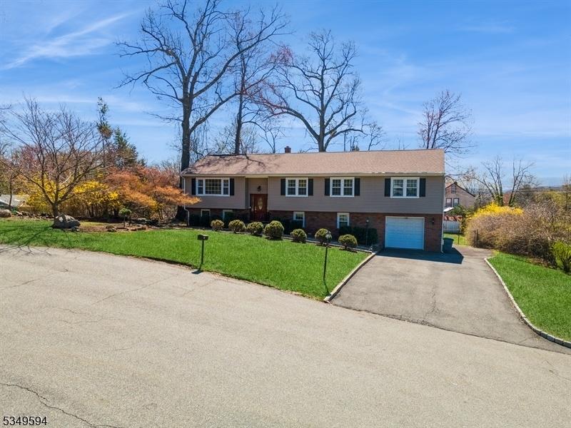 view of front of home featuring driveway, a garage, a front lawn, and brick siding