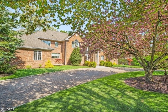 30 Mountain Ridge Dr, Livingston Twp, NJ 07039 - view of front of home with brick siding, a front yard, and a shingled roof
