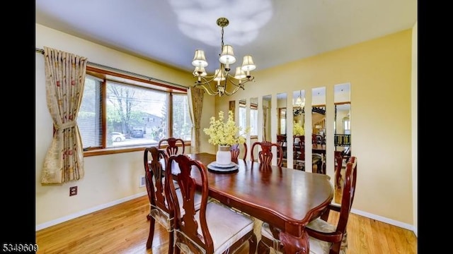 dining area featuring baseboards, light wood-style flooring, and a notable chandelier