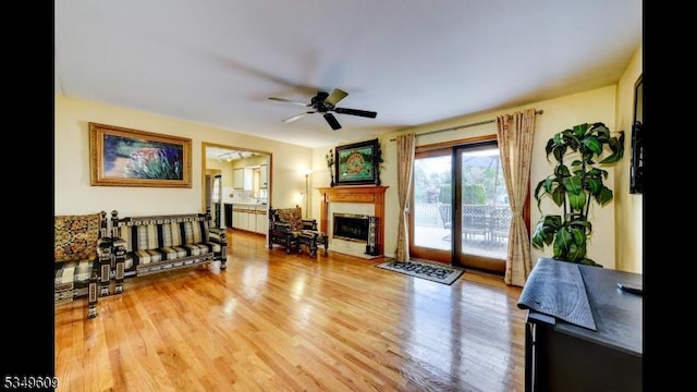 living room with ceiling fan, a fireplace, and wood finished floors