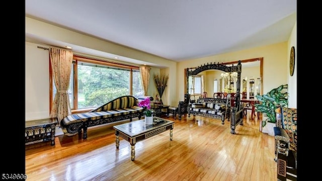living room with arched walkways, a notable chandelier, and wood finished floors