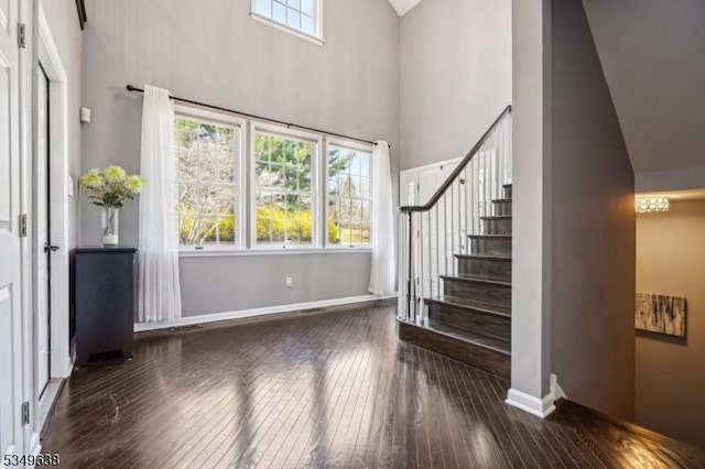 foyer featuring baseboards, a high ceiling, stairs, and hardwood / wood-style floors