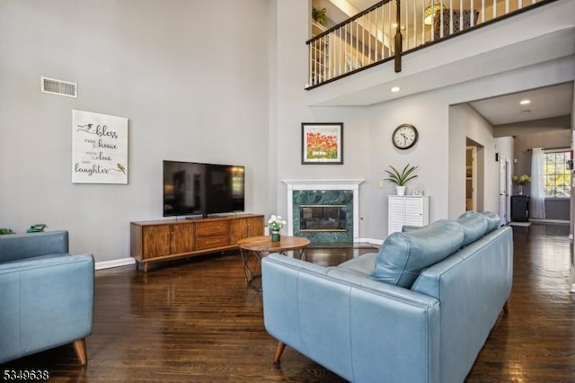 living area with visible vents, wood finished floors, and a towering ceiling