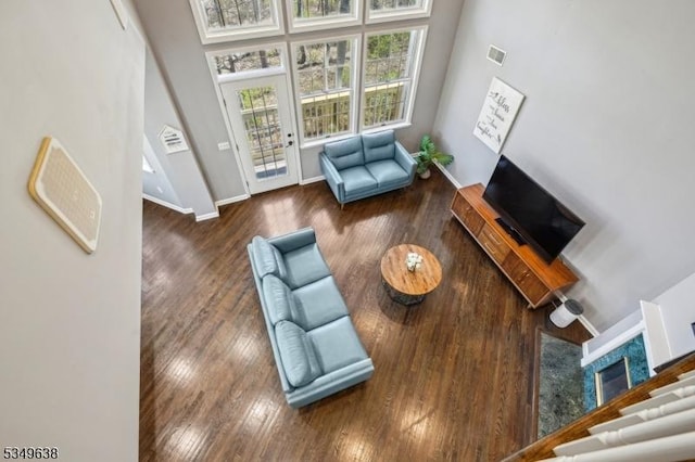 living room featuring visible vents, a high ceiling, baseboards, and wood finished floors