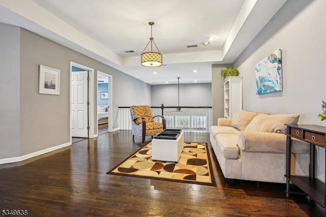living area with a raised ceiling, recessed lighting, baseboards, wood finished floors, and visible vents
