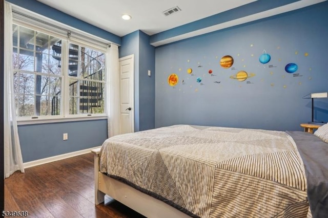 bedroom with baseboards, visible vents, and wood finished floors