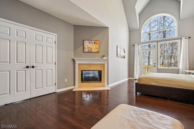 bedroom featuring a glass covered fireplace, baseboards, access to outside, and hardwood / wood-style flooring