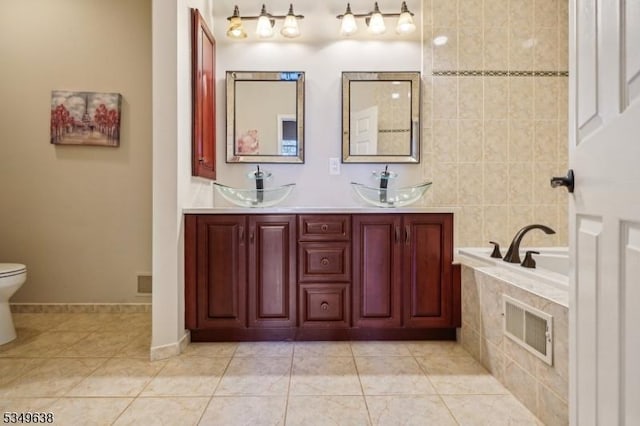 full bathroom featuring a relaxing tiled tub, tile patterned floors, visible vents, and a sink